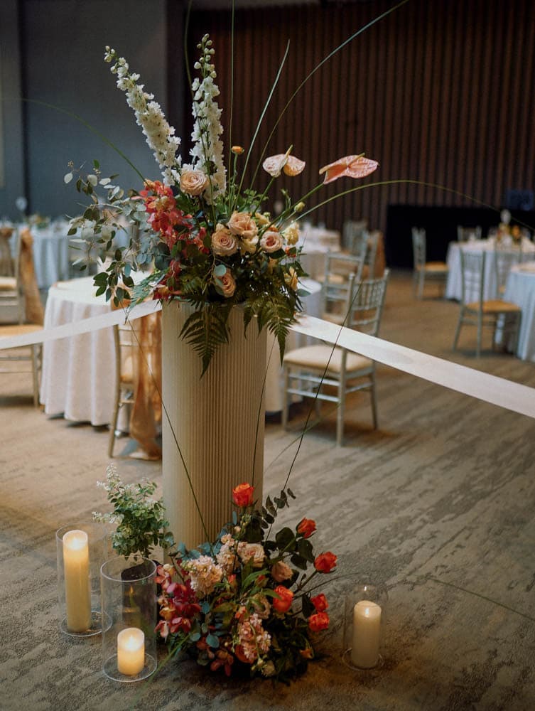 Lush floral wedding pedestal stand at Capella Hotel Singapore with candlelit aisle.