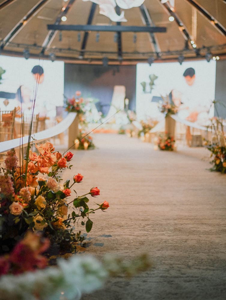 Wide cinematic view of tropical floral hedges for an march in aisle at Capella Hotel wedding ceremony.