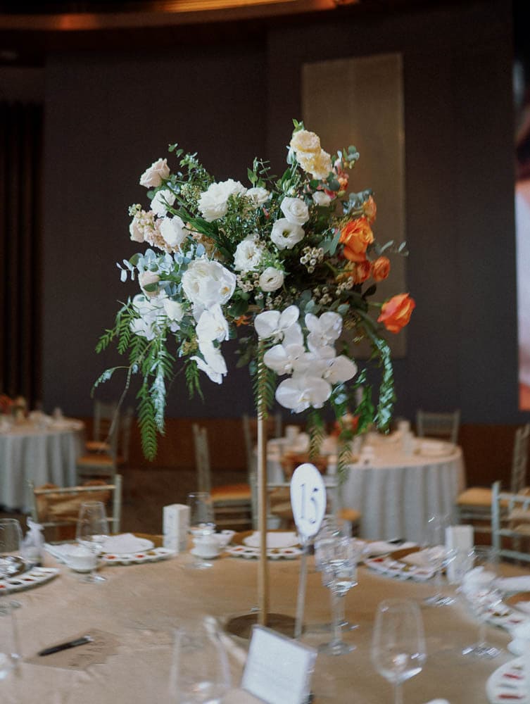 Tall centrepiece at Capella Hotel Singapore with warm tones floral mixed with white roses, orchids and greenery for a wedding.