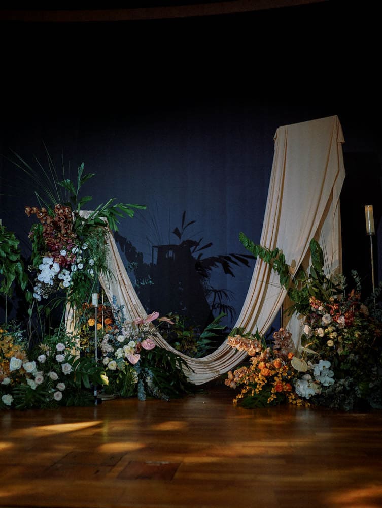 Full view of stage setup as backdrop wedding with tropical florals and drapes at Capella Hotel Singapore.