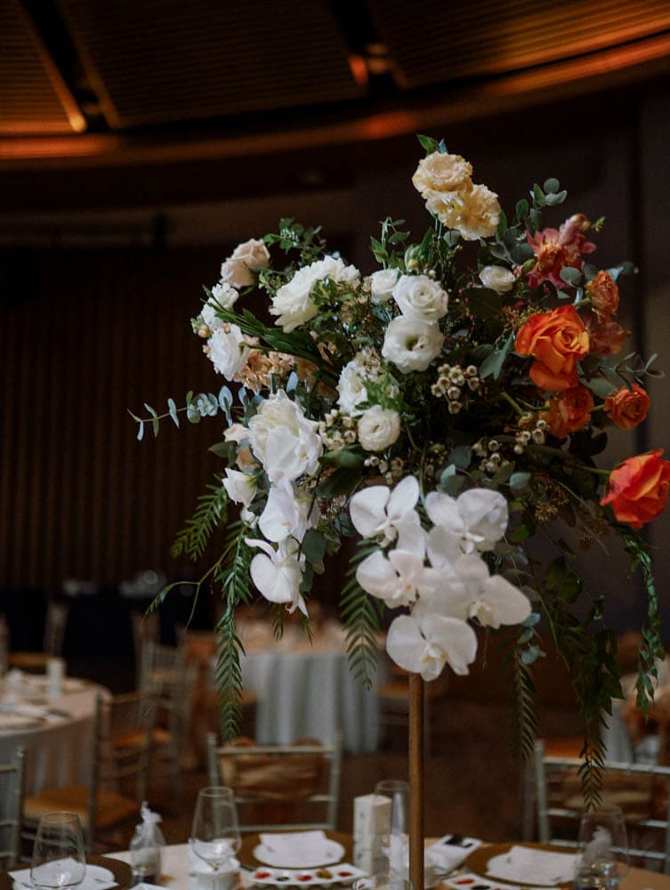 Tall centrepiece with roses and orchids in warm tones at Capella Hotel Singapore VIP table.