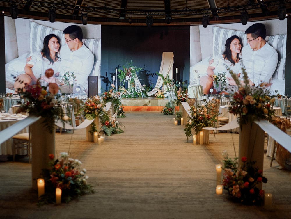 March-in aisle setup with tropical garden-inspired florals and pedestal stands to the stage at Capella Hotel Singapore.