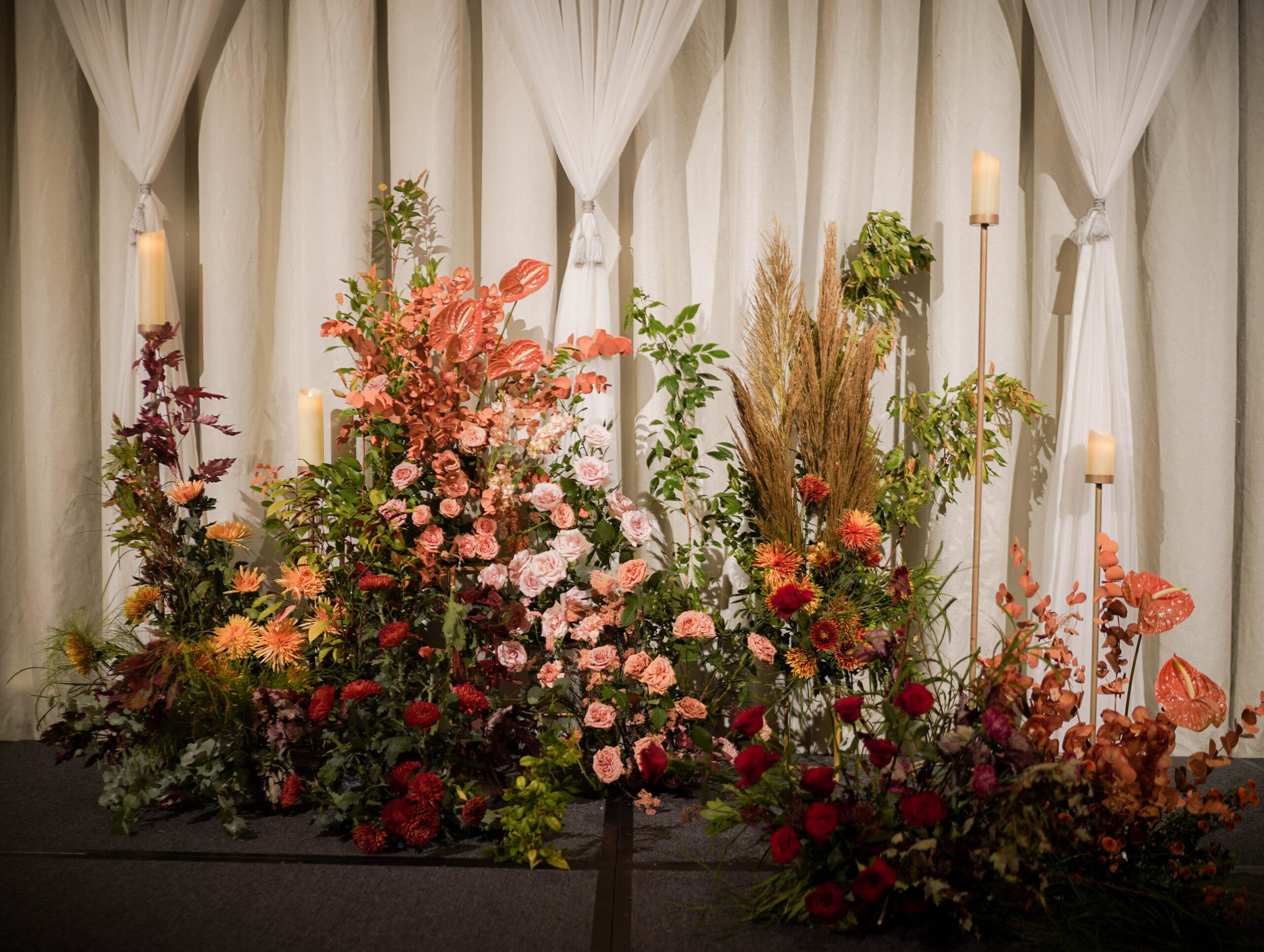 Landscape stage installation in terracotta, blush and red florals mixed with greenery and dried foliage at Four Seasons Hotel Singapore