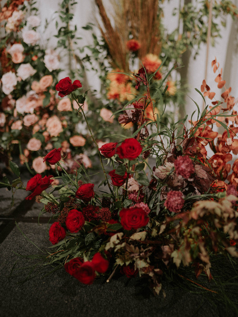 Close up of terracotta, blush and red roses with dried foliage and layered greenery styled in a lush autumn garden arrangement at Four Seasons Hotel Singapore