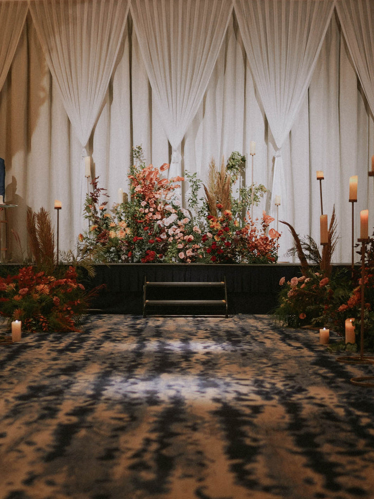 Full ballroom view of autumn garden wedding stage with terracotta and red floral landscape installation at Four Seasons Hotel Singapore