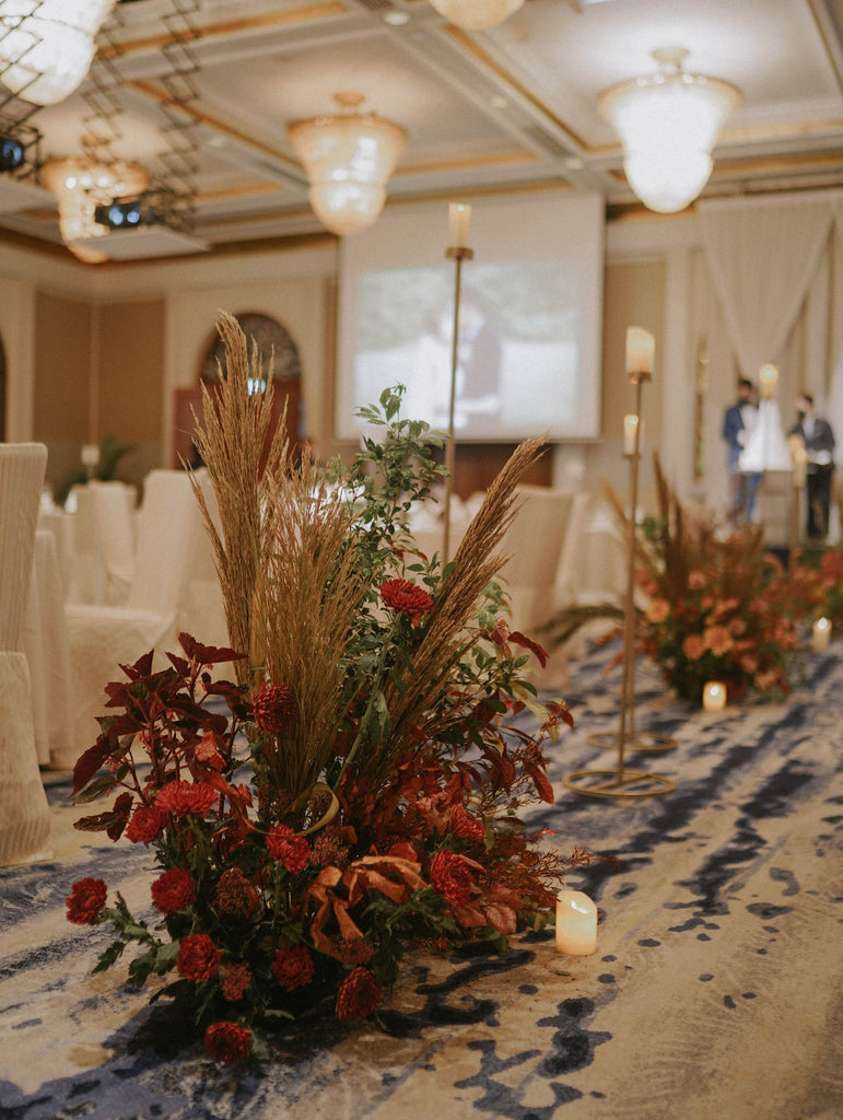 Lush autumn garden floral cluster with terracotta and red blooms mixed with dried foliage styled along the wedding aisle at Four Seasons Hotel Singapore