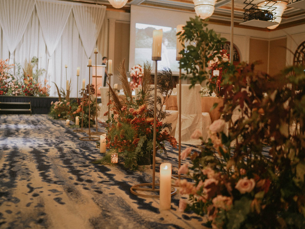 Autumn floral arrangement with candles lining the wedding aisle in terracotta and red tones at Four Seasons Hotel Singapore