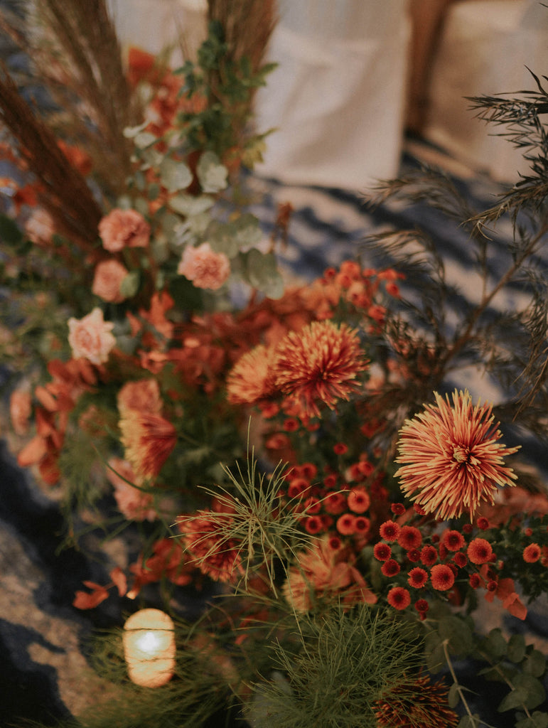 Close detail of blush roses, bronze spider mum and button chrysanthemum mixed with terracotta blooms and layered greenery in autumn wedding color palette at Four Seasons Hotel Singapore