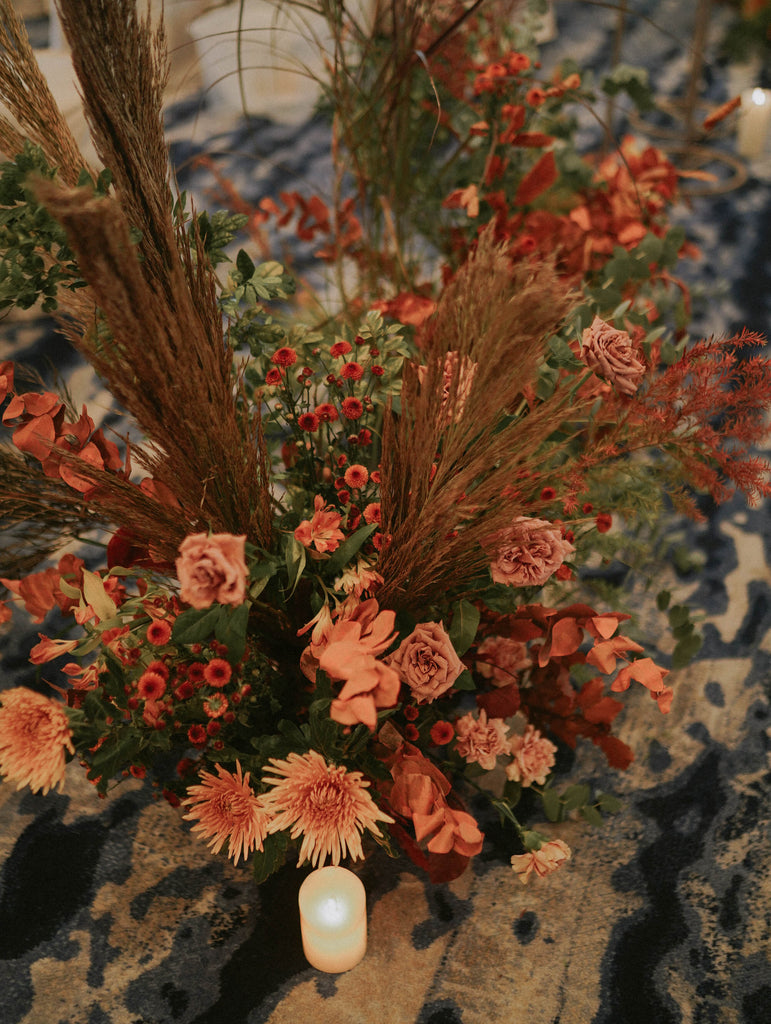 Autumn toned floral arrangement with terracotta roses and dried elements lining the wedding aisle at Four Seasons Hotel Singapore