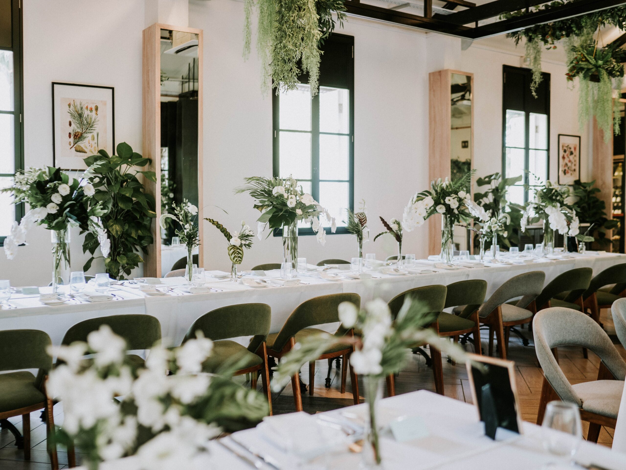 Glass vases filled with foliage and flowers on classic clean white table linens at wedding lunch Botanico The Garage restaurant Singapore