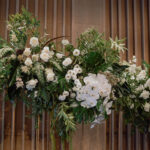 Overview of minimalist white and green cascading floral installation with tropical elements used as a wedding stage backdrop at Andaz Singapore