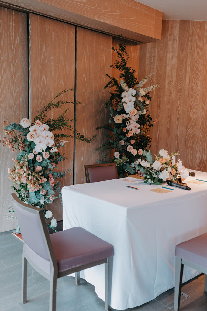 Solemnisation table styled with warm tone florals including roses, snapdragons and soft greenery in a clean vertical design at Andaz Singapore