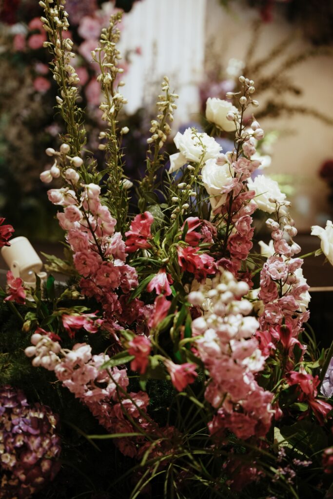 Floral detail showing soft purple snapdragon, delphinium mixed with white roses under warm lighting.