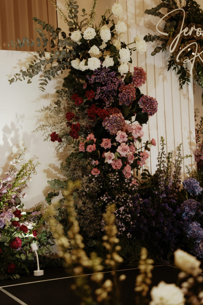 Floral wall blending soft white roses and lavender hydrangeas against panels.