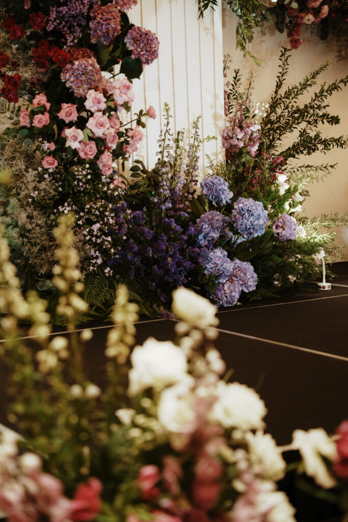 Ceremony florals with layers of white, lavender, and purple blooms in garden style.