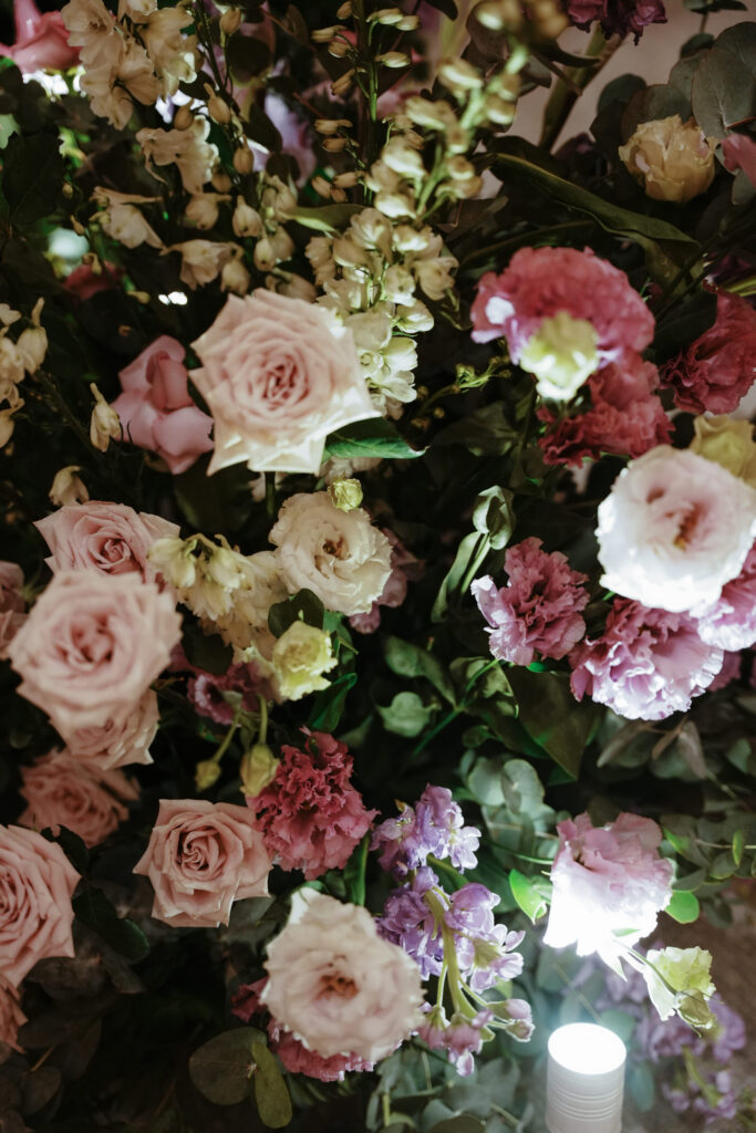 Close-up of lush florals in deep lavender and mauve tones under spotlight.