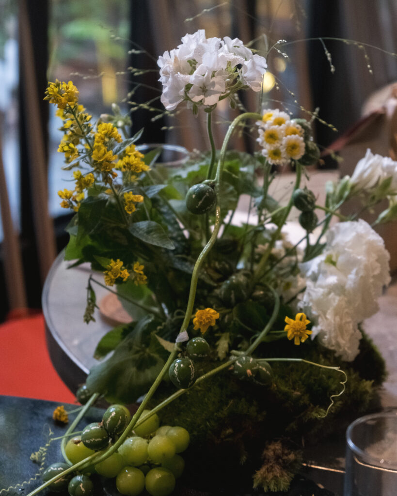 Organic-style table centerpiece with yellow filler blooms and vine detailing.