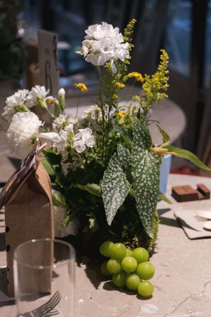 Close-up of green fruit-infused tablescape with patterned leaves and delicate wild yellow flowers.
