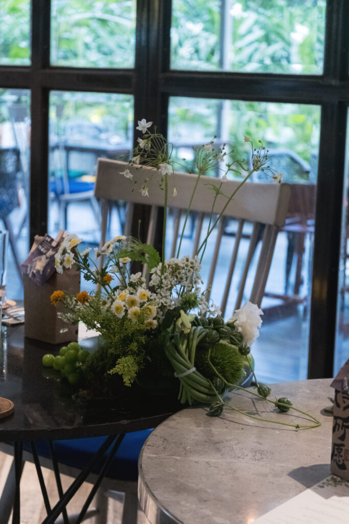 Natural light hitting the Open Farm Community venus farm-inspired floral installation with leafy green and delicate white flowers