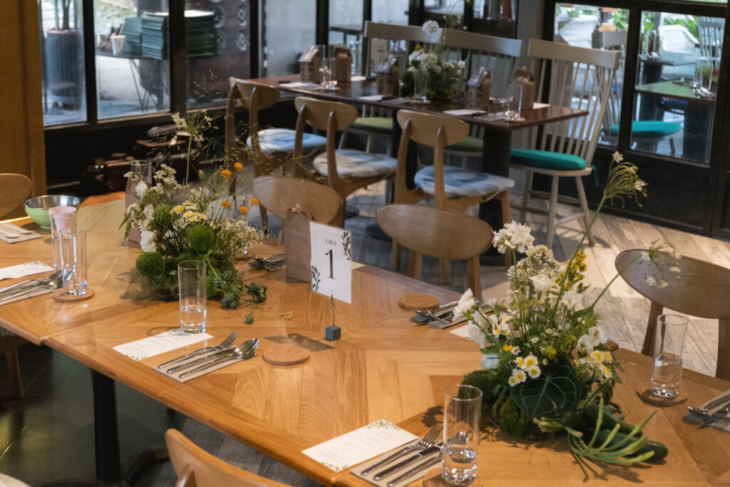 Rustic wedding tablescape with white chairs, floral centerpieces, and brown gift bags at Open Farm Community