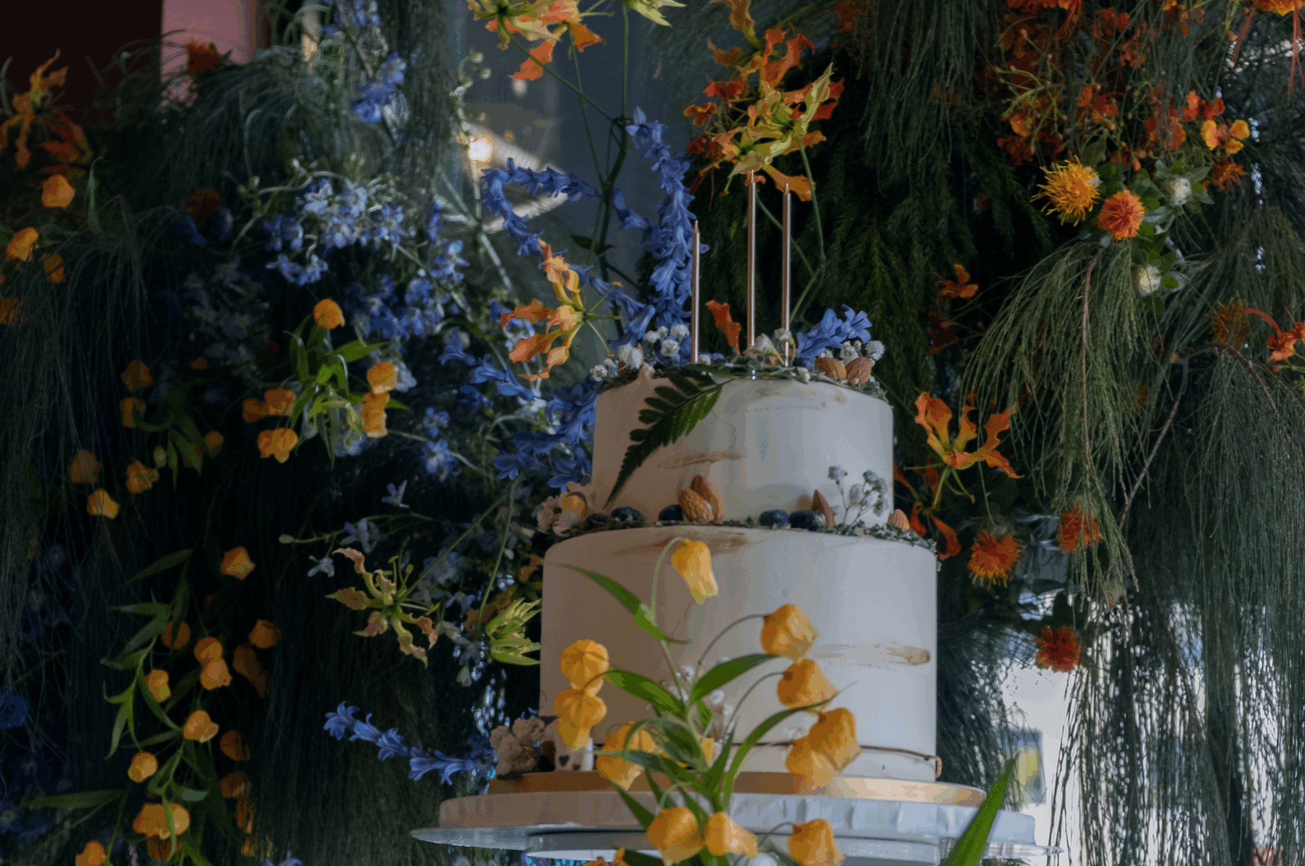 Floral-decorated cake table pedestal and backdrop.