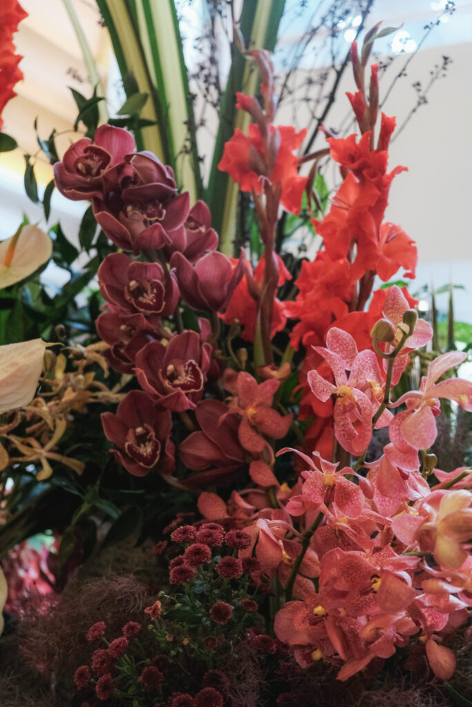 Rich pink orchids and bold foliage arranged for a dramatic hotel lobby installation.
