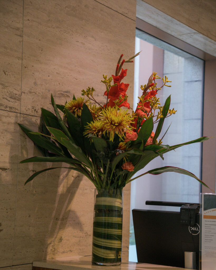Sleek tropical arrangement in reds and greens perfect for stylish hotel event decoration.