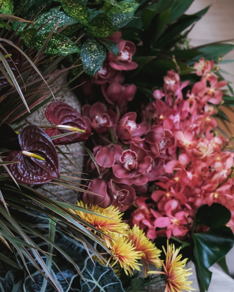 Colorful bold garden-style arrangement with dark foliage and red blooms for Resorts World Sentosa events.