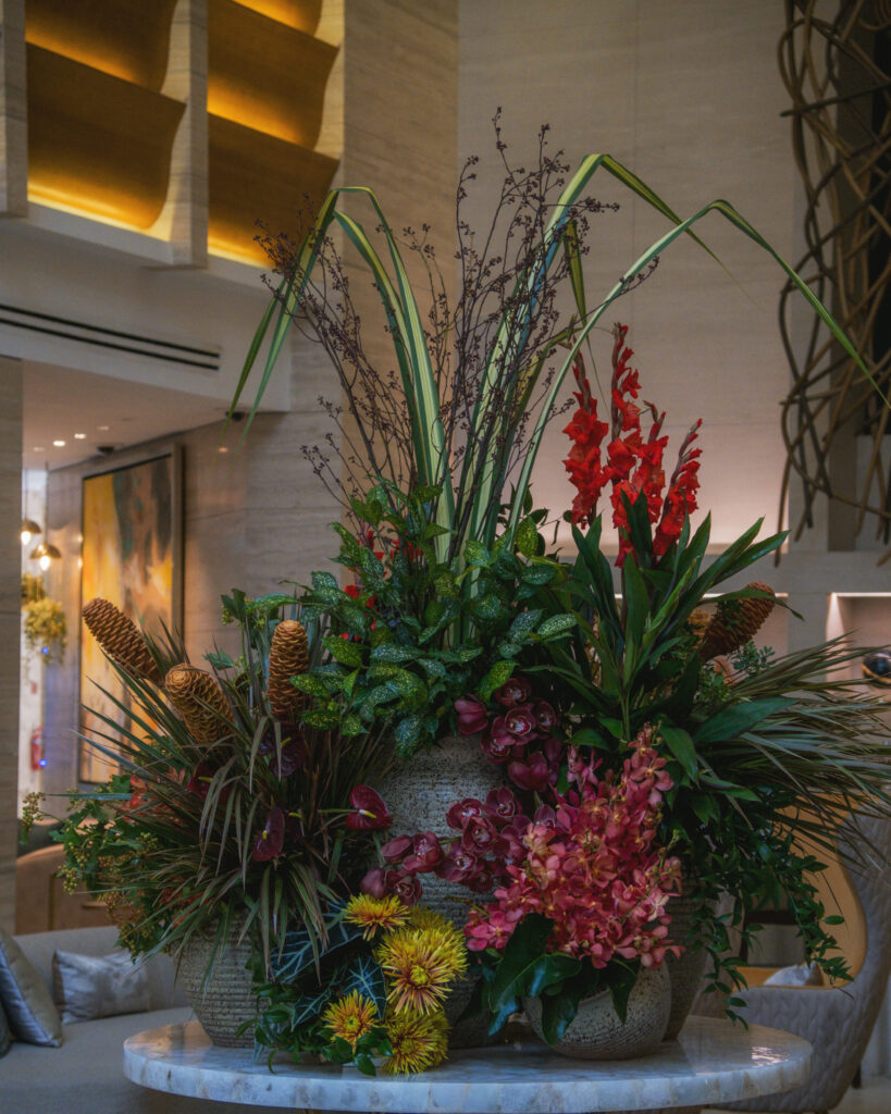 Eye-catching arrangement with bright reds and lush greenery for corporate styling.
