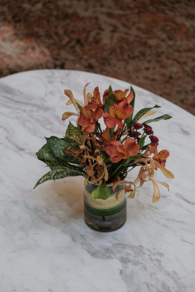 Dramatic red orchids and lush foliage designed centerpiece for impactful hotel lobby installations.