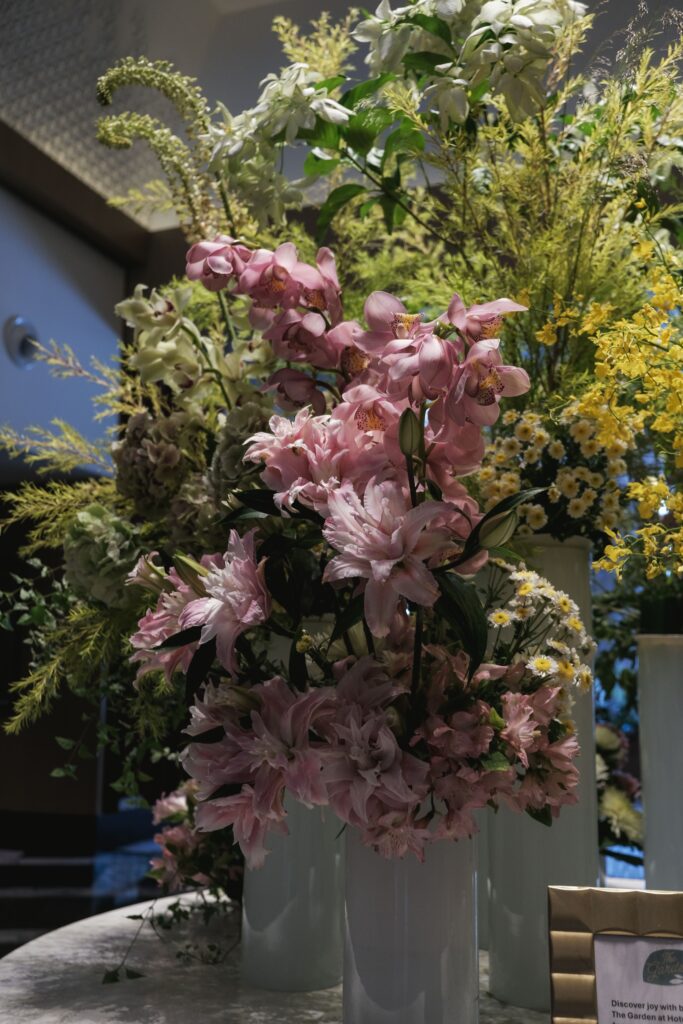 Pastel pink lilies and wild greens in a garden-inspired corporate floral setup at Hotel Michael.