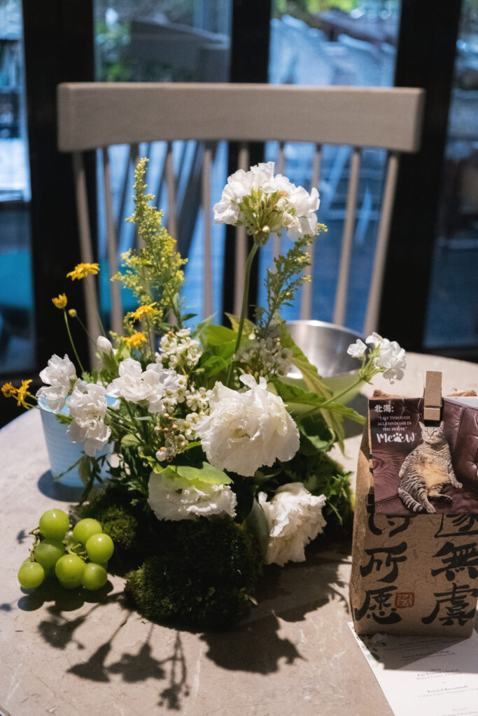 Close-up of table flowers with green grapes, white lisianthus, yellow marigolds, and mossy textures