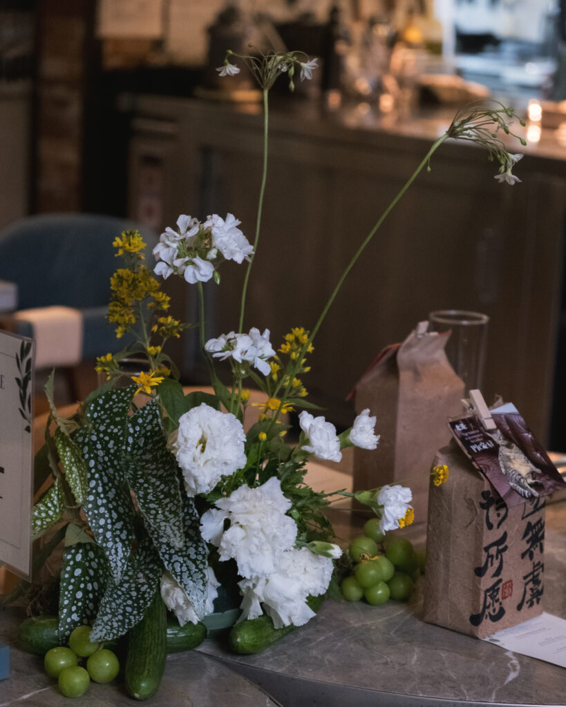 Rustic wedding tablescape with white chairs, floral centerpieces, and brown gift bags at Open Farm Community