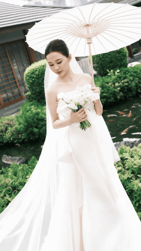 Bride holding a simple white bridal bouquet with classic styling for minimalist wedding at Raffles Hotel Singapore
