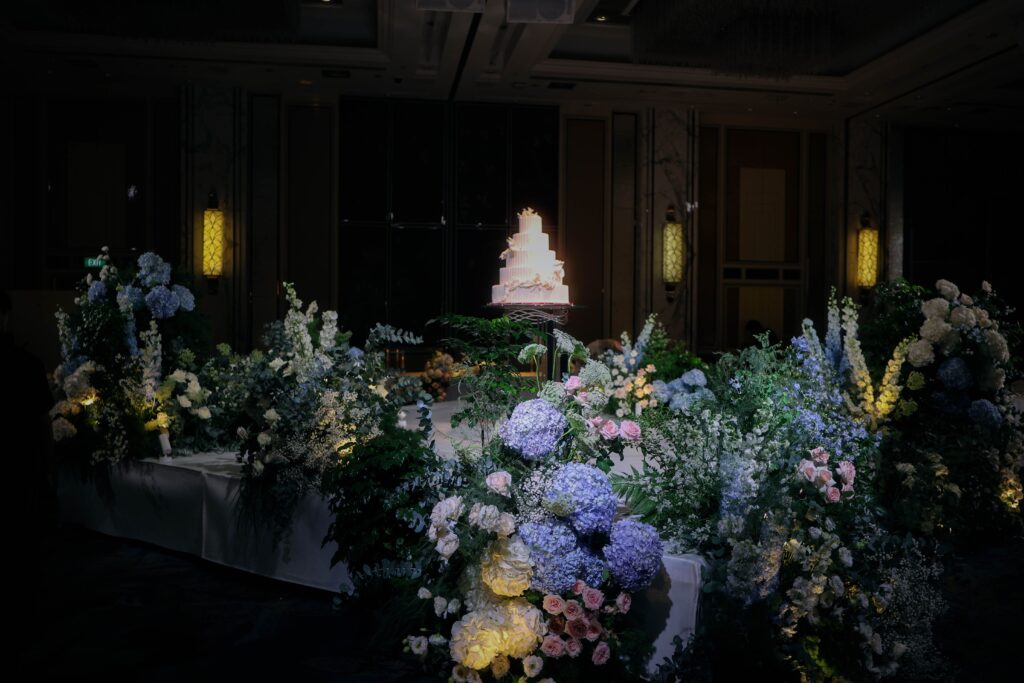 Layered floral arrangements framing a central ballroom platform using organic garden-style flowers and soft candlelight, Shangri-La Singapore