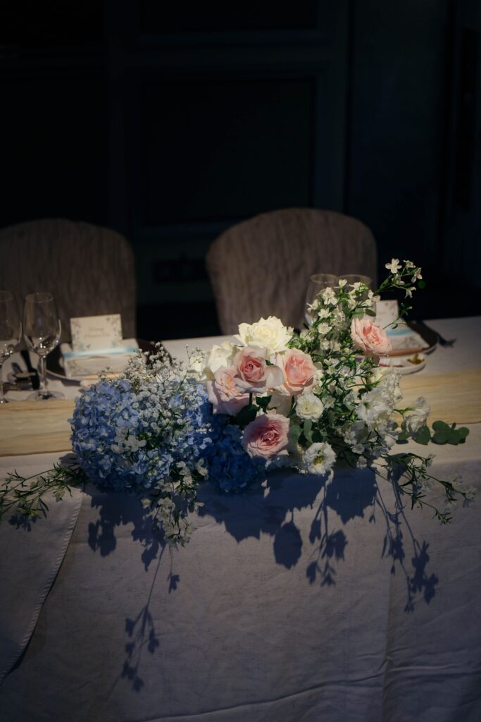 Intimate VIP table styled with low garden-style florals featuring hydrangeas, roses, and soft greenery in a luxury ballroom wedding, Shangri-La Singapore
