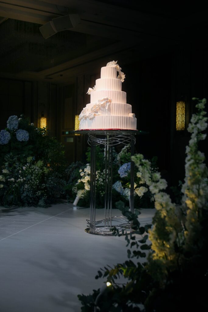 Wedding cake styled at the center of the ballroom with surrounding garden-inspired florals and soft lighting, Shangri-La Singapore