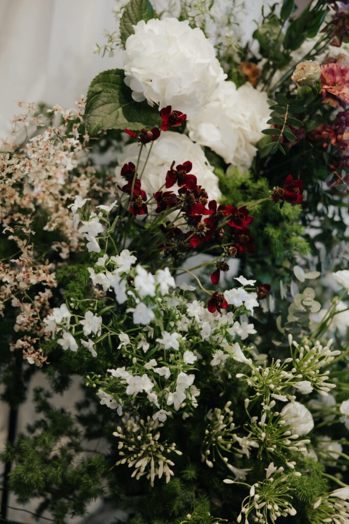 Organic floral arrangement with burgundy blooms, cream roses and layered foliage at Andaz Singapore
