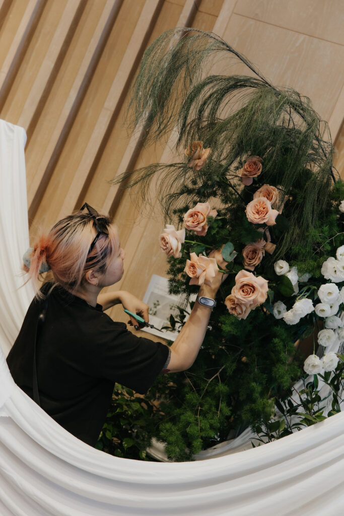 Florist adjusting flowing white drapes integrated with wild organic florals on wedding stage at Andaz Singapore