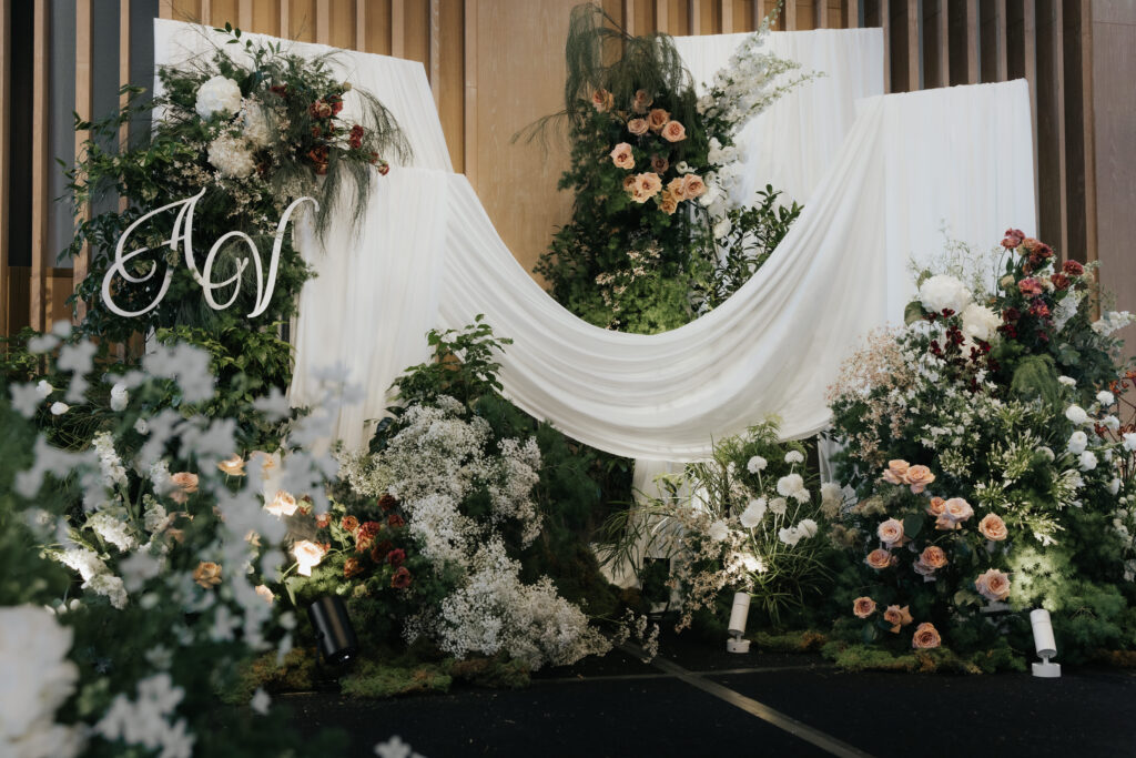 Finished wedding stage arrangement with cascading drapes and wild organic flowers in antique garden theme at Andaz Singapore