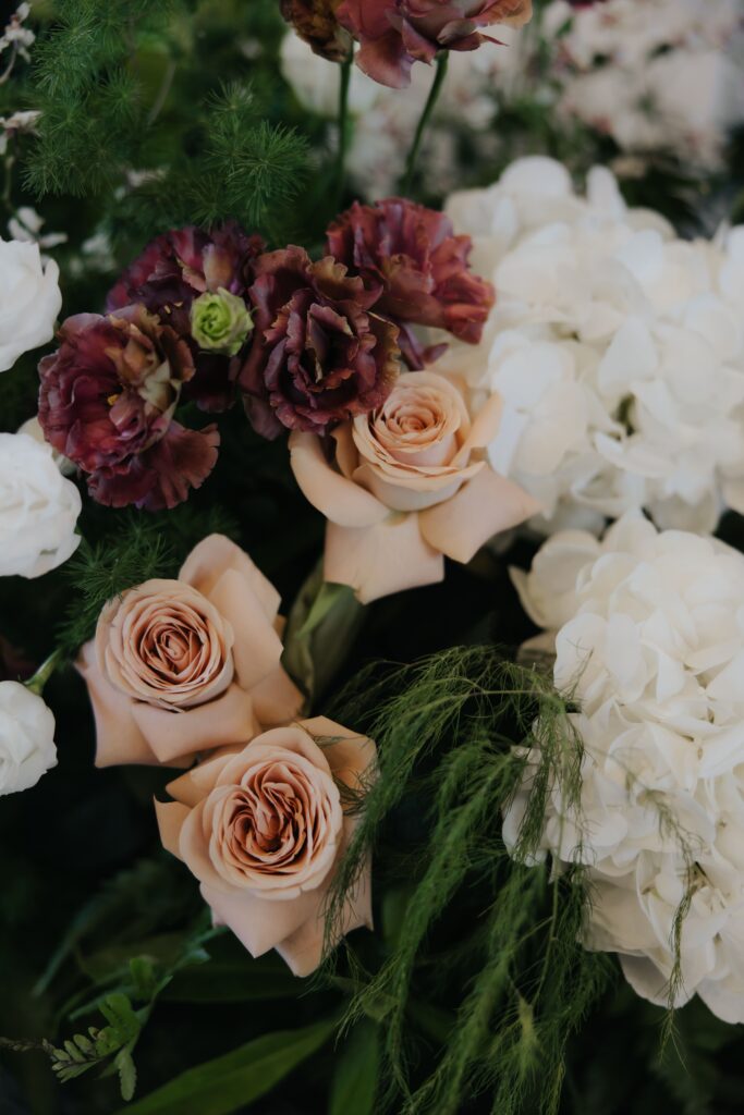 Close up of stage floral arrangement featuring roses, hydrangeas and carnations in white brown green palette at Andaz Singapore