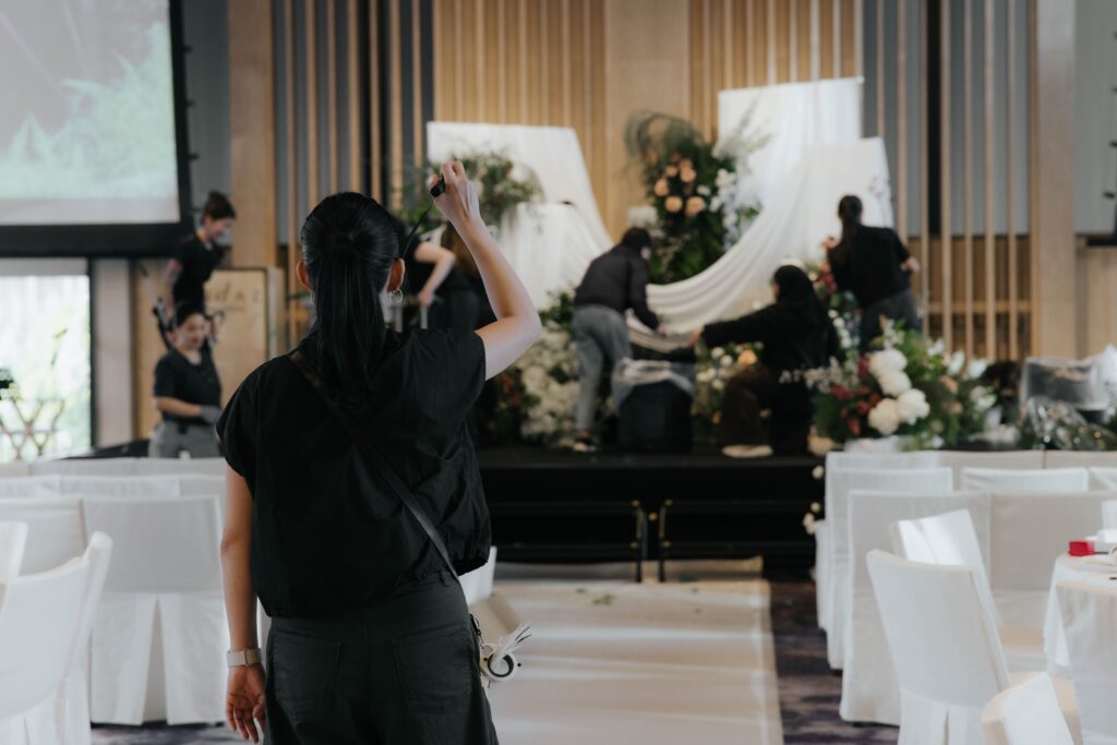 Floral team setting up organic antique garden stage installation with layered greenery and flowing drapery at Andaz Singapore