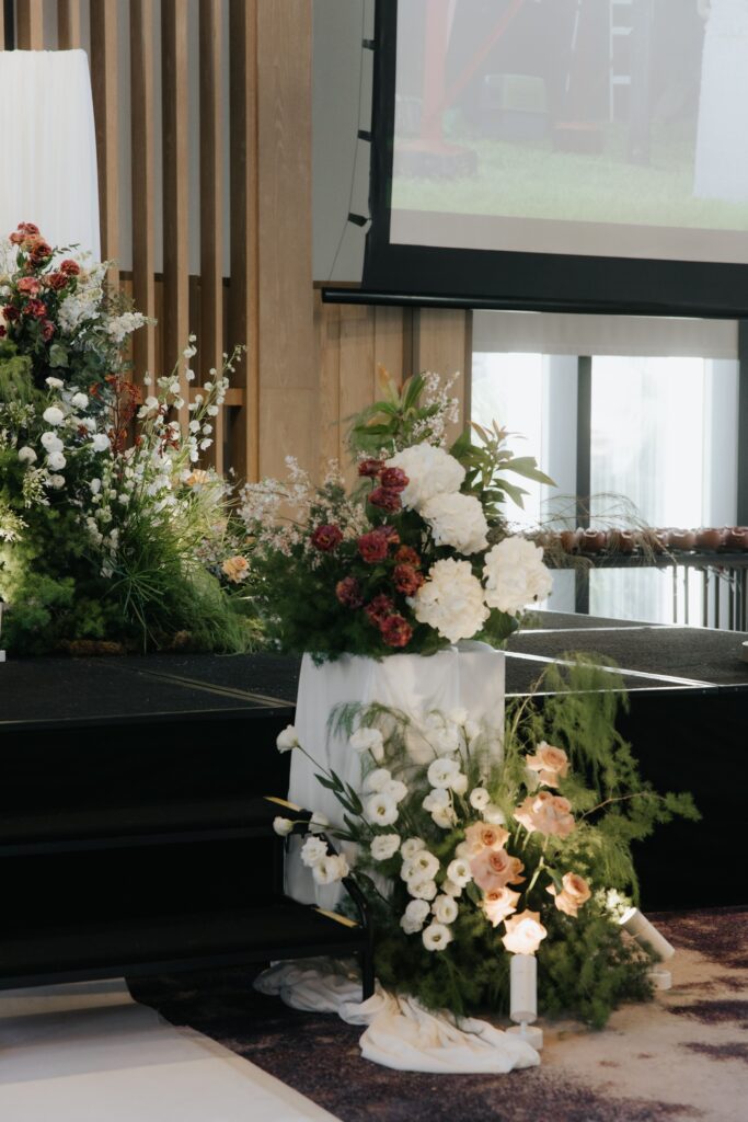 Vertical floral installation positioned beside stage steps with roses and greenery at Andaz Singapore