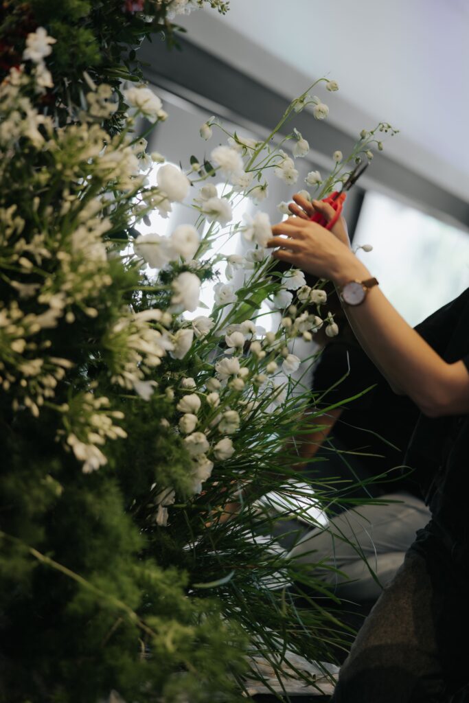 Close up of team member arranging roses and greenery into organic antique garden composition at Andaz Singapore