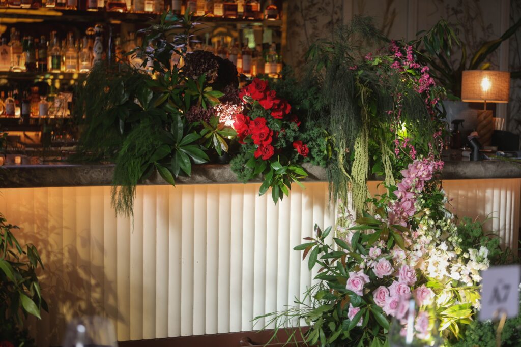 Botanical wedding installation at the bar featuring white hydrangeas, pink roses, red roses and layered greenery for a modern wedding, Claudine Singapore