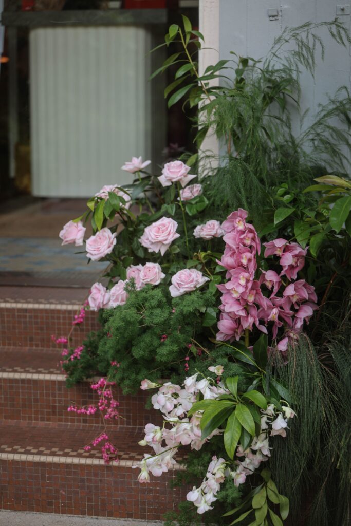 Side view of entrance floral installation with white orchids, pink roses and orchids with cascading greenery styled for an intimate wedding, Claudine Singapore