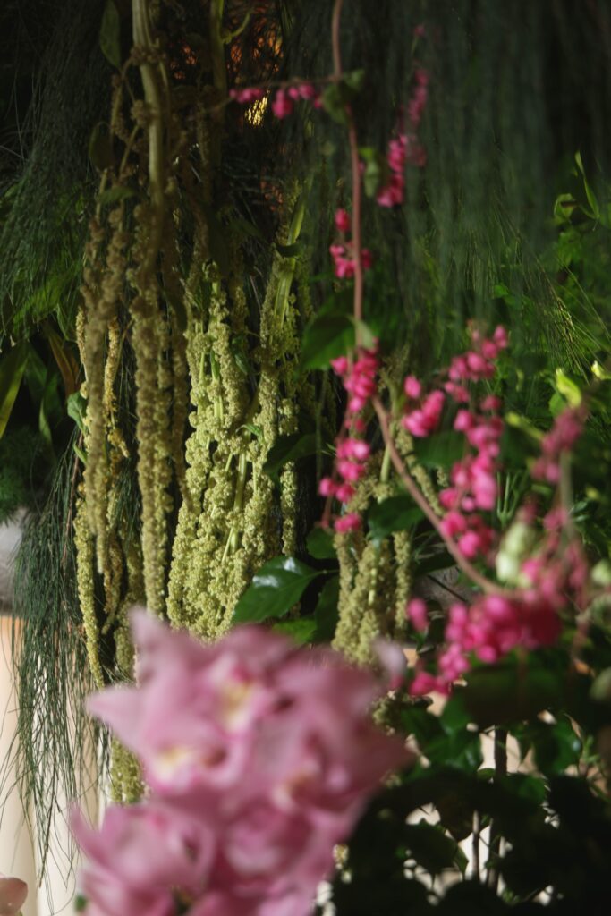 Close-up of cascading green amaranthus with soft blurred pink orchids in a modern botanical wedding installation, Claudine Singapore