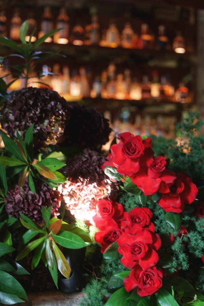 Close-up of red roses with lush green foliage in a modern botanical bar arrangement for an intimate wedding dinner, Claudine Singapore