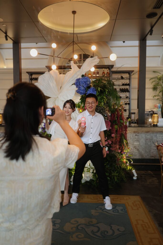 Guests taking photos in front of the floral backdrop installation styled with fresh flowers and large paper flowers inside the restaurant, Empress Restaurant Singapore