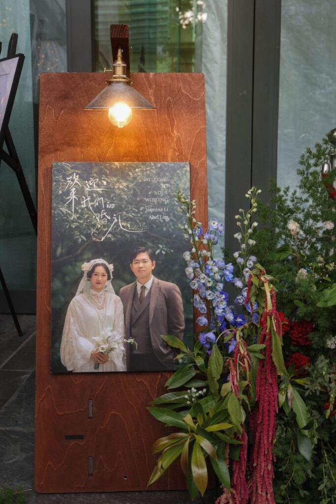 Wedding welcome sign crafted in dark wood with the couple’s photo displayed, styled with fresh florals and greenery at the restaurant entrance, Empress Restaurant Singapore